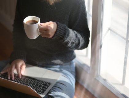 Frau mit Kaffee und Laptop